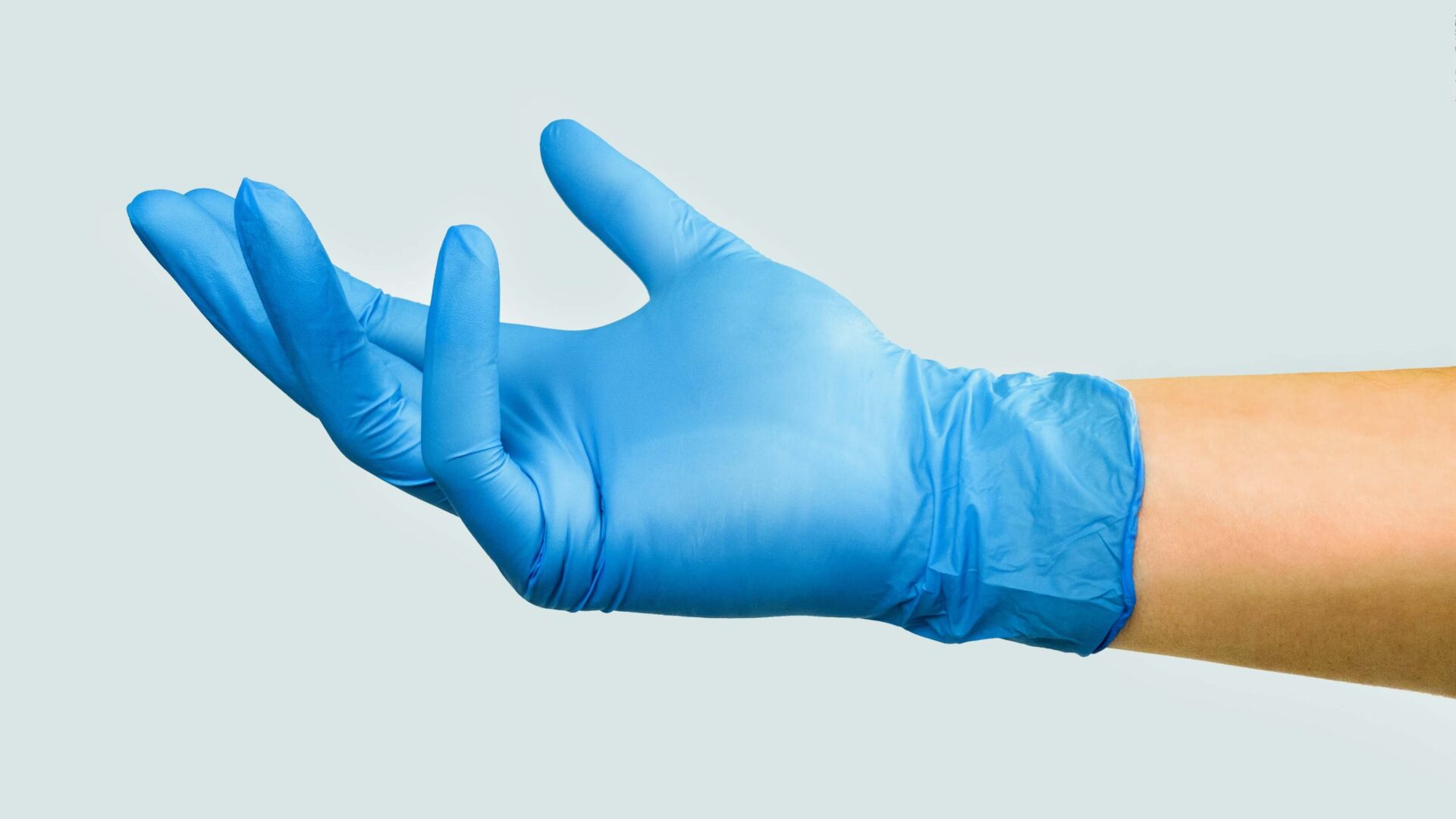 A hand with blue gloves on it's arm.